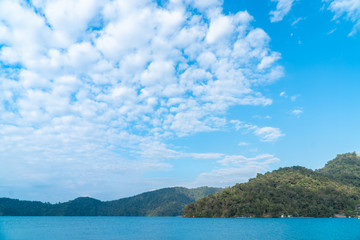 Obraz premium Mountains landscape scene with blue sky and white clouds over green water in sun moon lake in Taipei, Taiwan