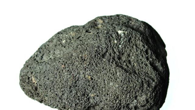 Vesicular basalt rock from Santorini volcano rotating on white background.