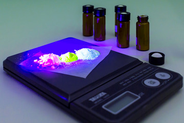 The laboratory scale of black color on table with organic material on surface and opened bottles...
