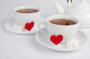 Two white cups of tea with tea labels in the form of red hearts. Tea for Two