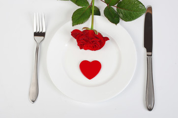 Fototapeta na wymiar Served table with white dishes, red heart, red rose on white background