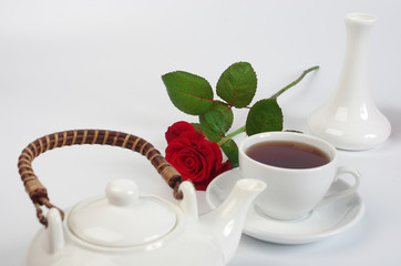 Cup of tea, teapot, red rose on white background