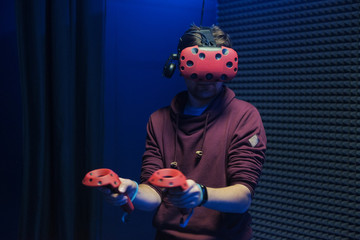 Man plays virtual reality using glasses, gamepad and headset.