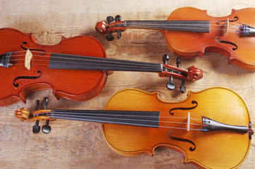 Three violins on a wooden table