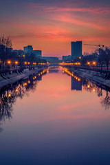 Fototapeta premium Vibrant cityscape shot early morning before sunrise in Bucharest with a river in the foreground