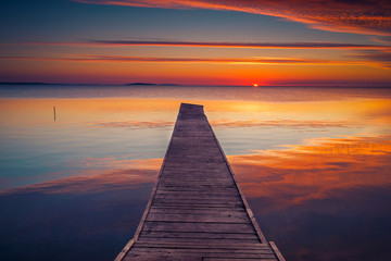 Fototapeta na wymiar Pontoon by the lake at sunrise with bneautiful clouds on the sky