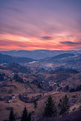Small village placed in a valley between mountains seen from above at sunset shot in Romania with a long exposure