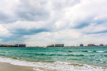 Obraz premium Horizon of Seascape, water waves at Jumeirah Beach under cloudy sky in Dubai, United Arab Emirates