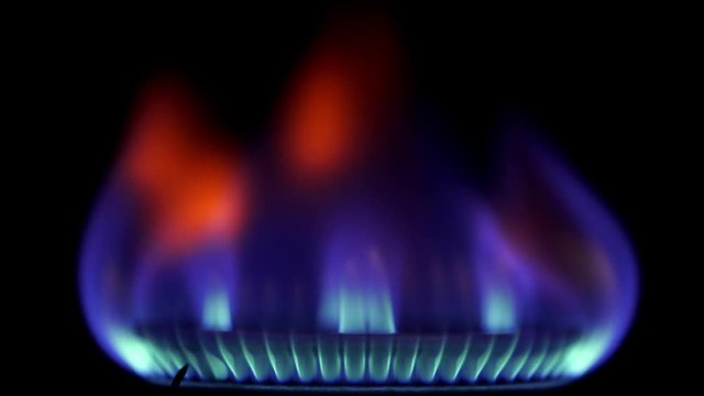 Stove top burner igniting into a blue cooking flame in slow motion 120fps. Close up.