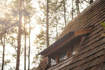 Close up garret window of the little wooden cottage house roof in forest. Log cabin hut with...