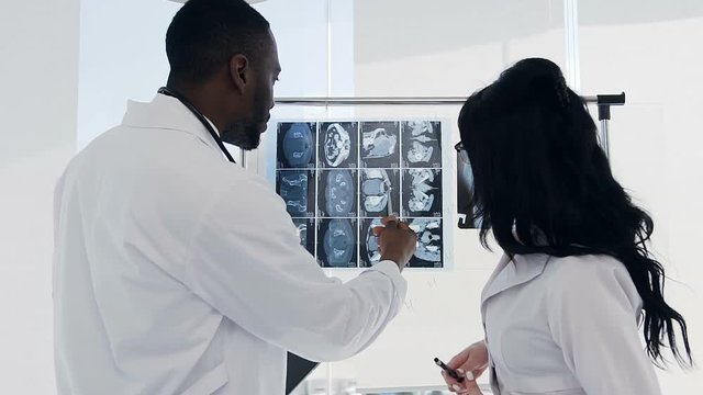 Two doctors discussing xray prints of patient bones in the hospital.