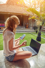 Freelancer girl with smartphone, coffee / tea and laptop on a home porch.