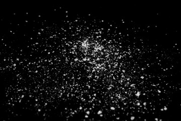 white crystalline powder on a black background. sugar dust 