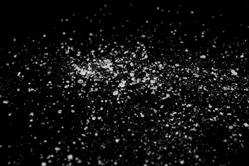 Fototapeta premium white crystalline powder on a black background. sugar dust 