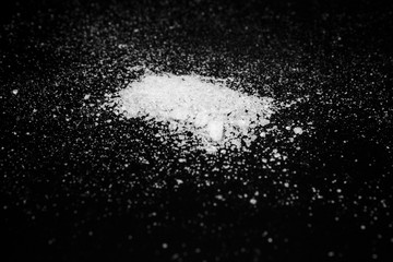 Fototapeta na wymiar white crystalline powder on a black background. sugar dust 