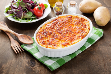 Potato casserole with meat on  wooden table.