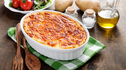 Potato casserole with meat on  wooden table.