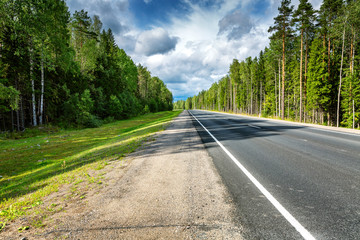 Fototapeta na wymiar Direct road route through the forest. Smooth asphalt surface.
