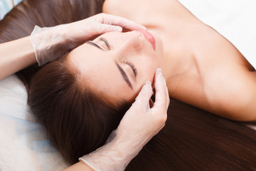 Fototapeta na wymiar Beautiful brunette on facial massage in beauty salon