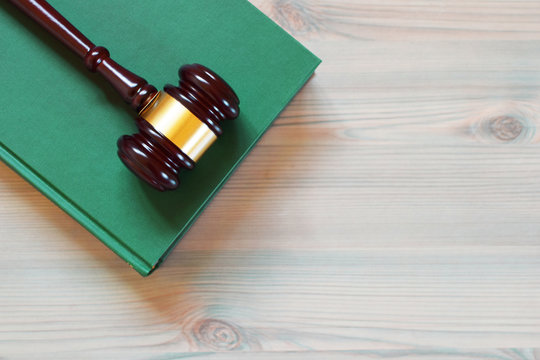 Judges gavel or law mallet on green law book on wooden texture table. Legal law, justice system, education and judgement  concept.