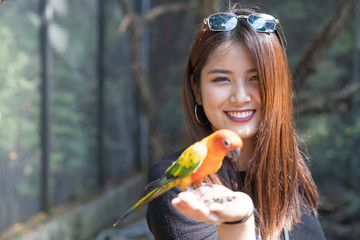Asian beautiful woman enjoying with love bird on hand and body.