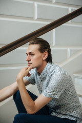 A man in a white plaid shirt and blue trousers poses for advertising men's clothing. Shooting for men's clothing store