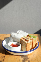 Sandwiches in white plate with ketchup and mayonnaise on a wooden table.