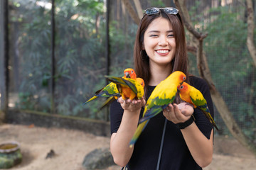 Asian beautiful woman enjoying with love bird on hand and body.