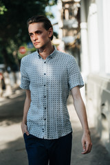 A man in a white plaid shirt and blue trousers poses for advertising men's clothing. Shooting for men's clothing store