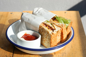 Sandwiches in white plate with ketchup and mayonnaise on a wooden table.