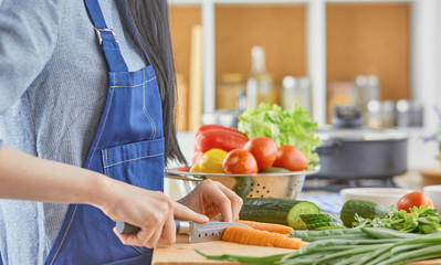 A young woman prepares food in the kitchen. Healthy food - vege