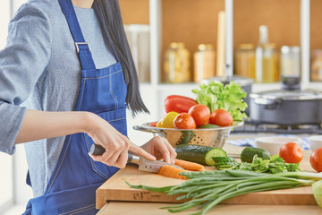 A young woman prepares food in the kitchen. Healthy food - vege