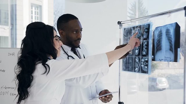 Two young doctors discussing xray prints of patient in the conference room.