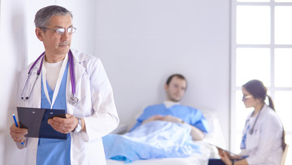Doctor checking heart beat of patient in bed with stethoscope