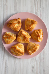 Home-baked cottage cheese biscuits on pink plate over white wooden background, top view.