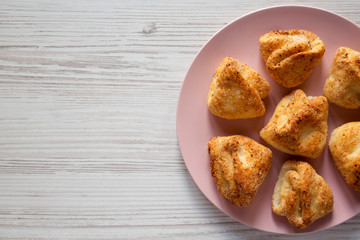 Home-baked cottage cheese biscuits on pink plate over white wooden surface, top view. Flat lay, overhead. Copy space.