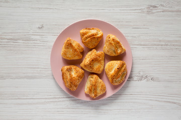 Home-baked cottage cheese biscuits on pink plate over white wooden surface, top view. Flat lay, overhead, from above.