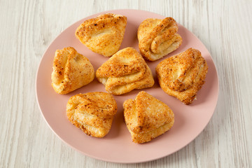 Homemade cottage cheese biscuits on pink plate over white wooden surface, low angle view. Close-up.