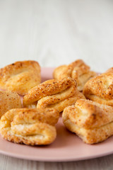 Home-baked cottage cheese biscuits on pink plate over white wooden surface, side view. Closeup.