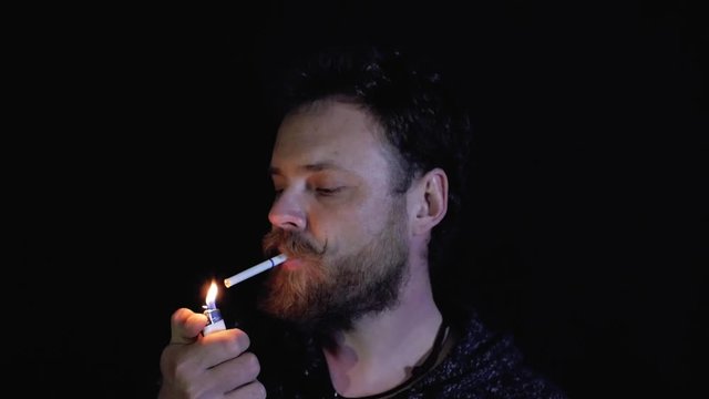 eccentric man with a beard and mustache smoking a cigarette on a black background