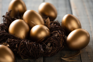 Happy easter! golden of Easter eggs in nest and Feather on wooden background.