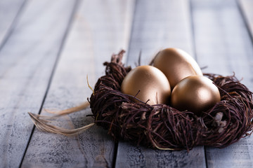 Happy easter! golden of Easter eggs in nest and Feather on wooden background.