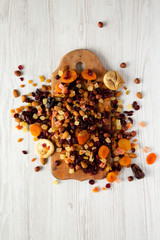 Dried fruits and nut mix on rustic wooden board over white wooden background, top view. Close-up.