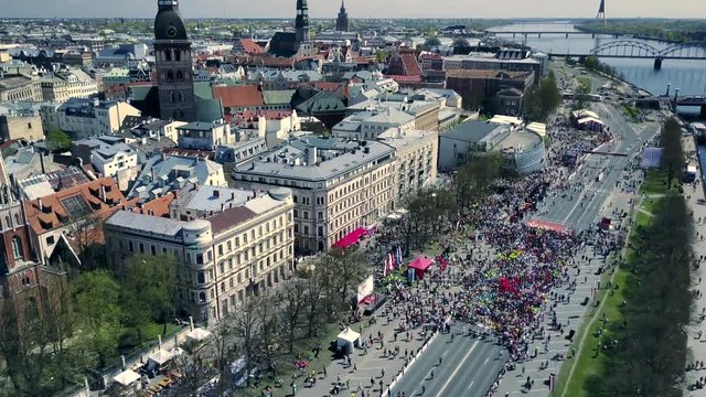 Aerial view from drone on crowd of people who is running on marathon event. City landscape.