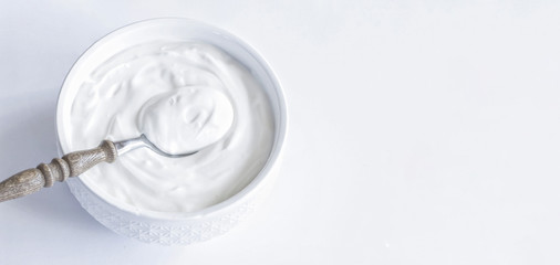 sour cream in a cup and spoon top view. background with fresh thick sour cream on the table. copy space. place for text.