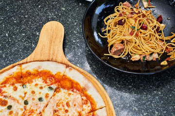 Spicy and chili spaghetti in black dish and pizza serve on wood dish	