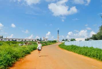 Obraz premium Chinese girl walks on country road to petrochemical plant