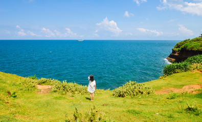 Obraz premium Chinese girl stands on grassland looking at ocean
