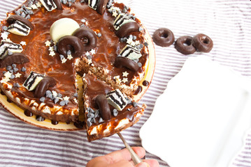 Homemade cake three chocolates with hand puting slice to plate. Mousse glaze darkness decoration cake.