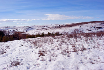 Fototapeta na wymiar Snowy hills, winter landscape, blue cloudy sky background